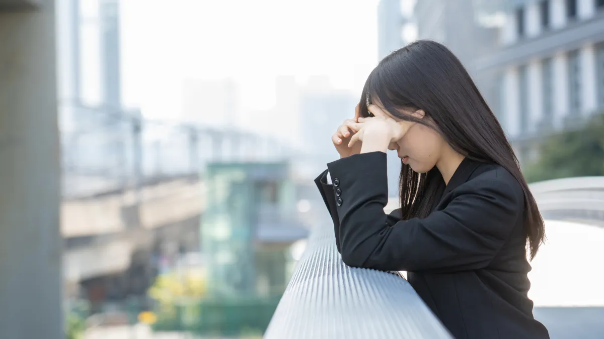 スーツを着た女性が頭を抱えている