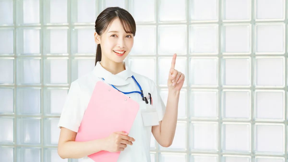 白衣を着た女性が指をさしている