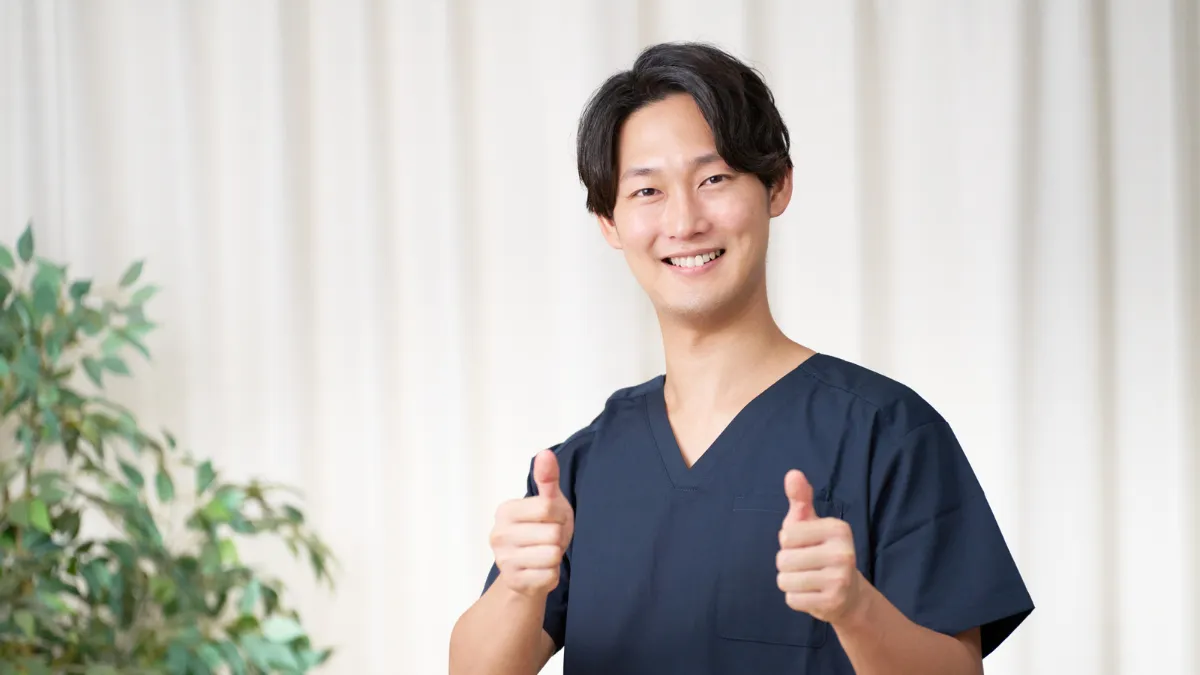 スクラブを着た男性が笑顔でこちらをみてる