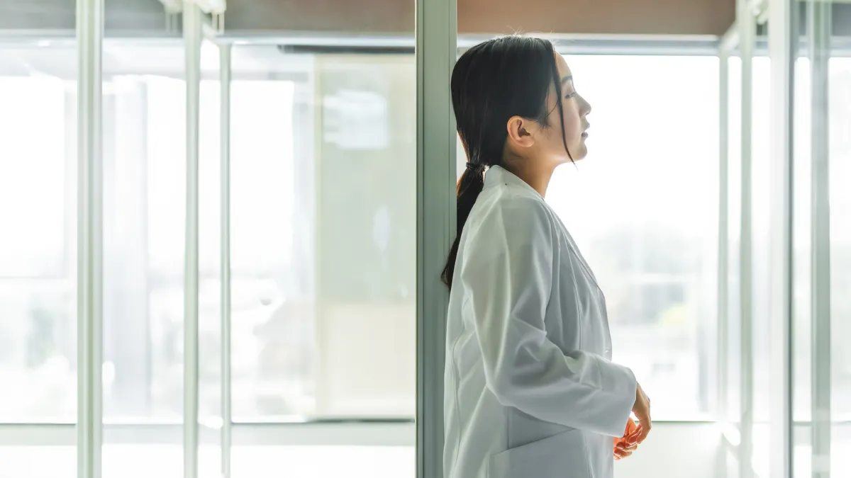 白衣を着た女性はが暗い部屋で遠くを見ている