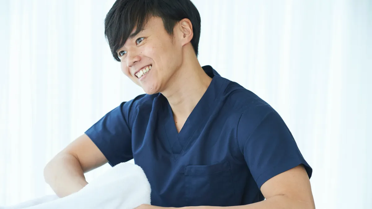 スクラブの男性が笑顔で施術してる