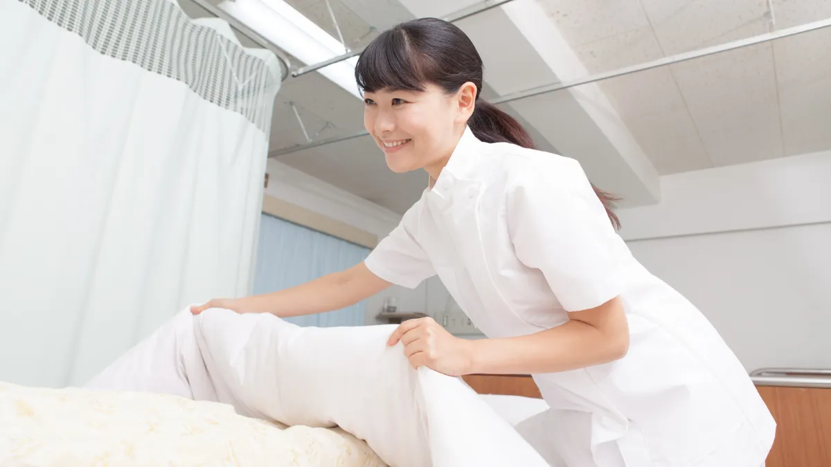 白衣の女性が寝ている人に布団をかけている