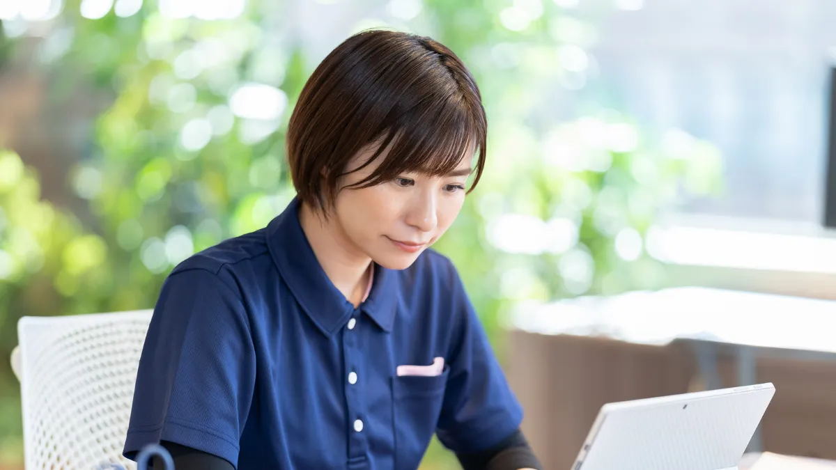 白衣を着た女性がパソコン作業をしている