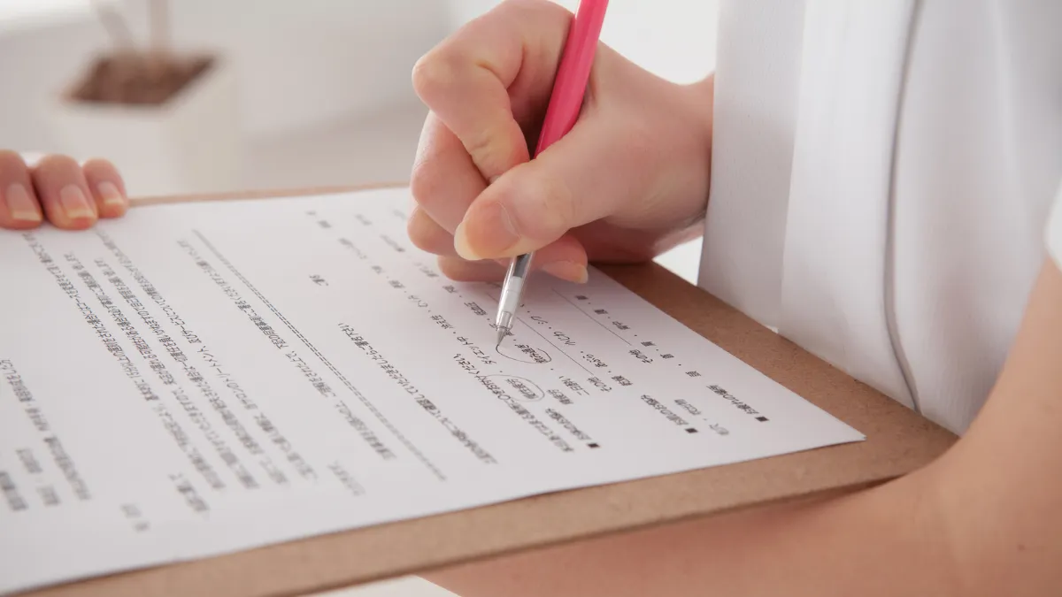 白衣を着た女性が紙に何か記載している