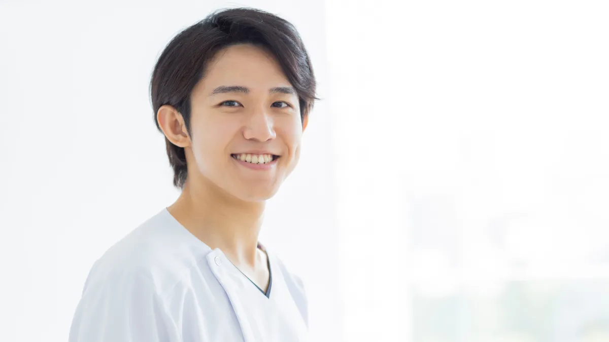 スクラブの男性が笑顔でこっちを見ている