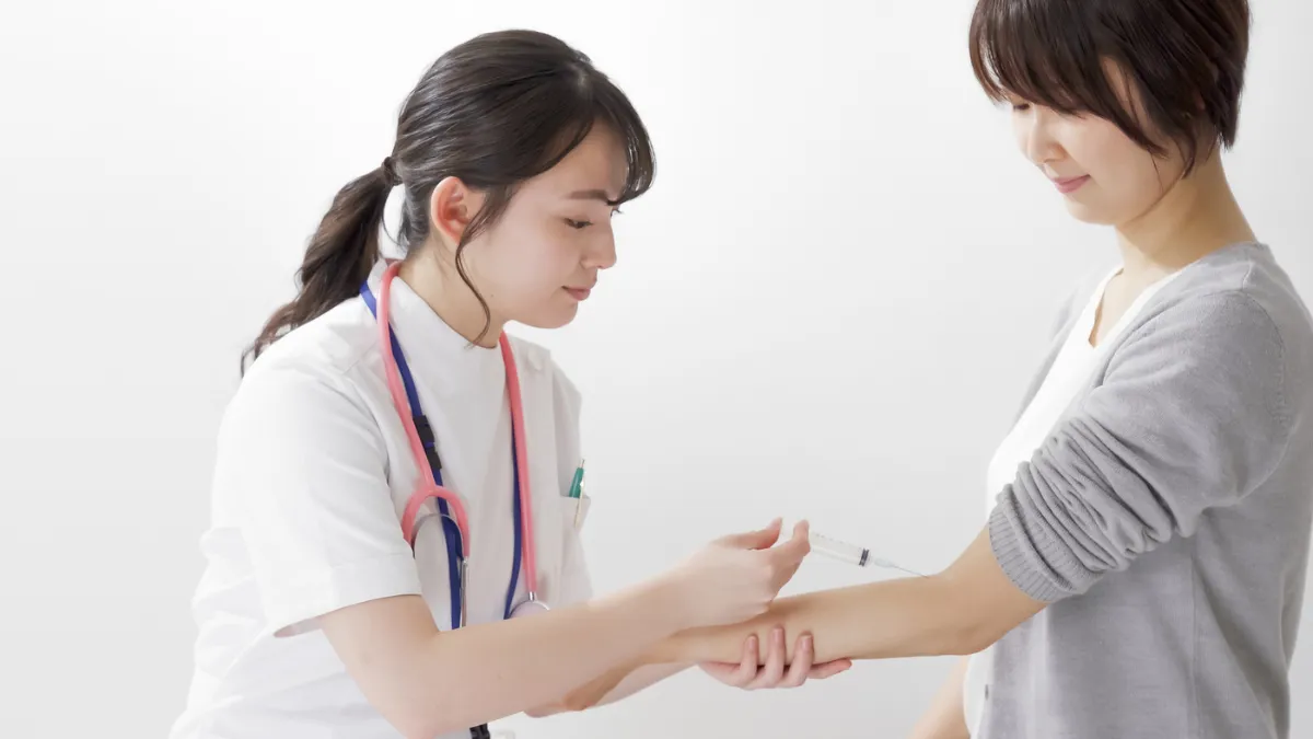 白衣を着た女性が注射をしている