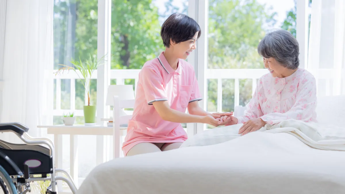 患者宅で患者の手を握る訪問看護師
