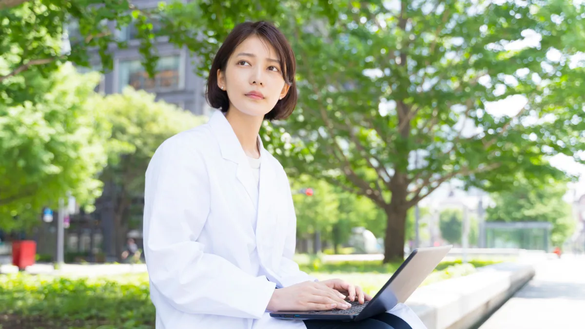 薬剤師の女性が外でパソコンを触っている