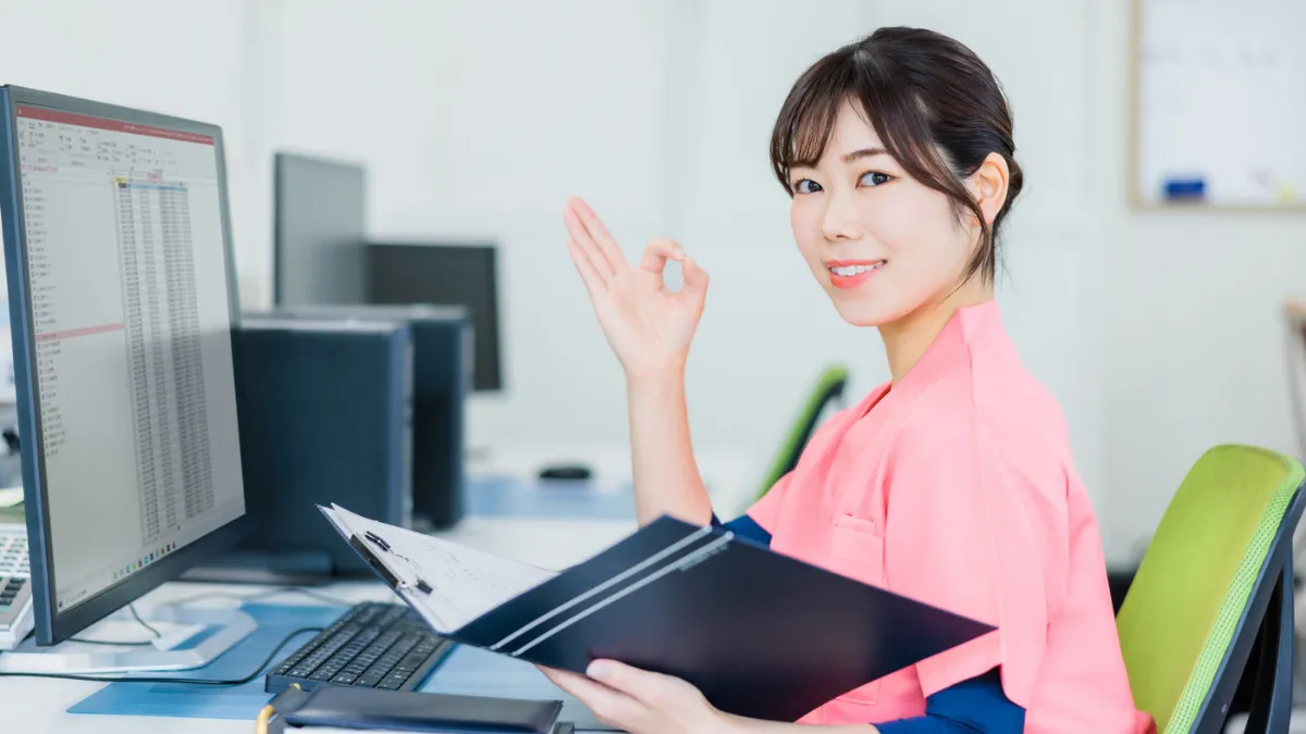 パソコンの前でスクラブの女性が◎を作っている