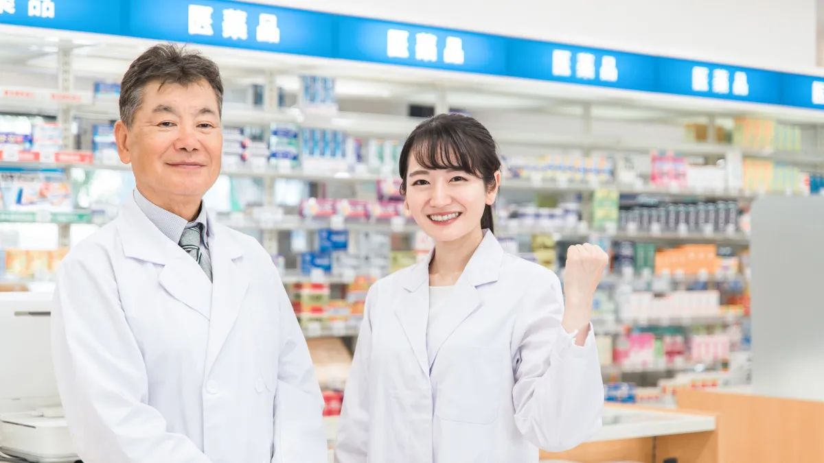 医薬品売り場の前で男女が笑顔で立っている