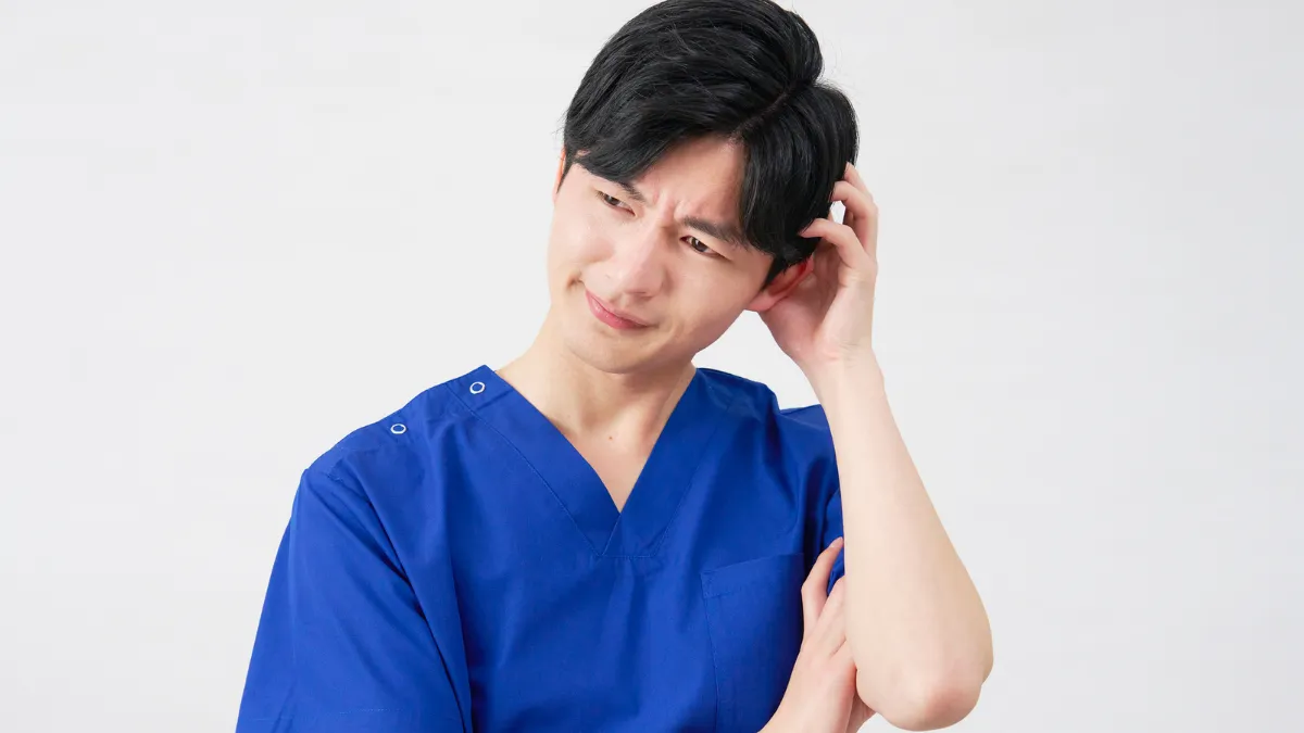 あん摩マッサージ指圧師 悩む 困る 頭をかく 男性施術者