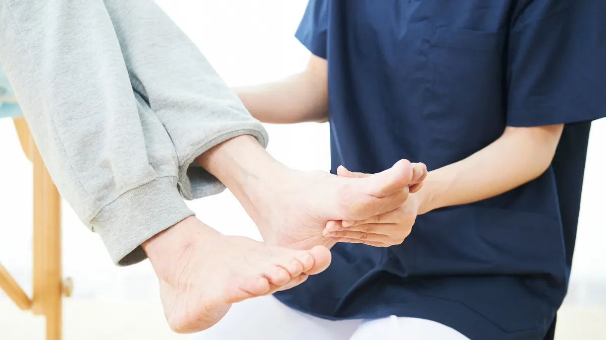 患者の足の可動域を確認する柔道整復師