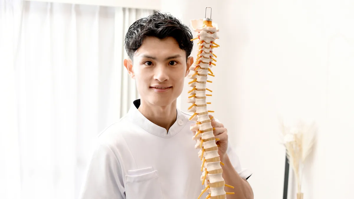 人骨模型を持って笑顔を見せる鍼灸師の男性