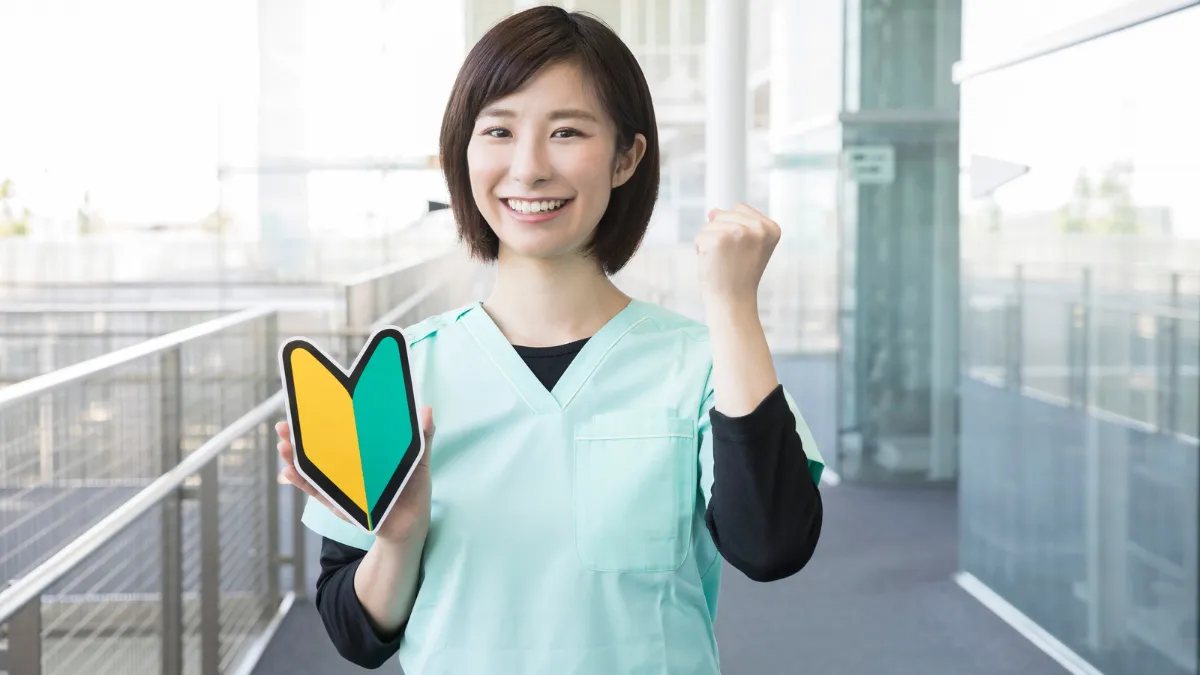 初心者マークを持ちガッツポーズをする看護師