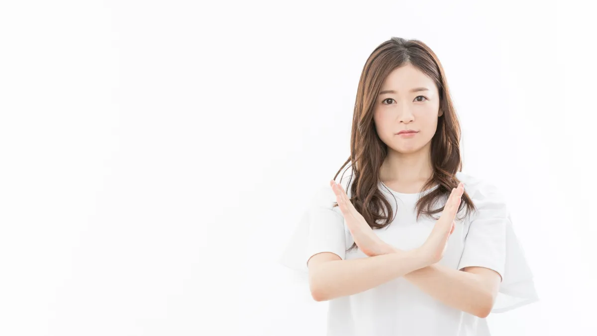 手でバツのジェスチャーをする女性