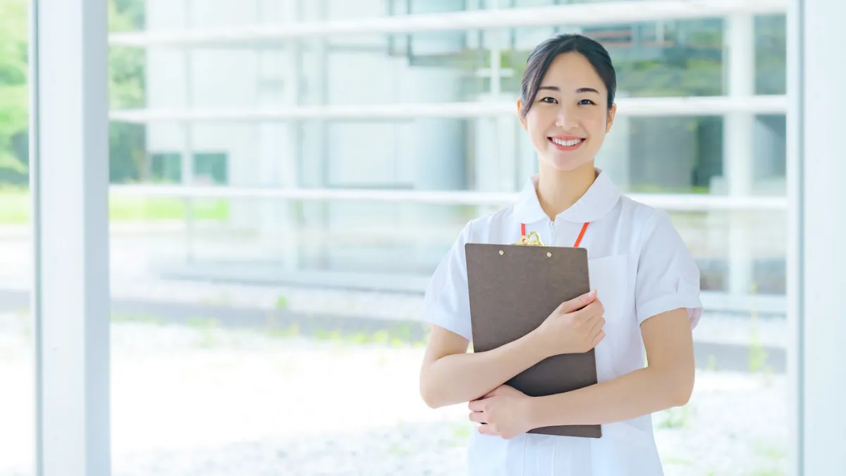 明るい表情でバインダーを抱える看護師