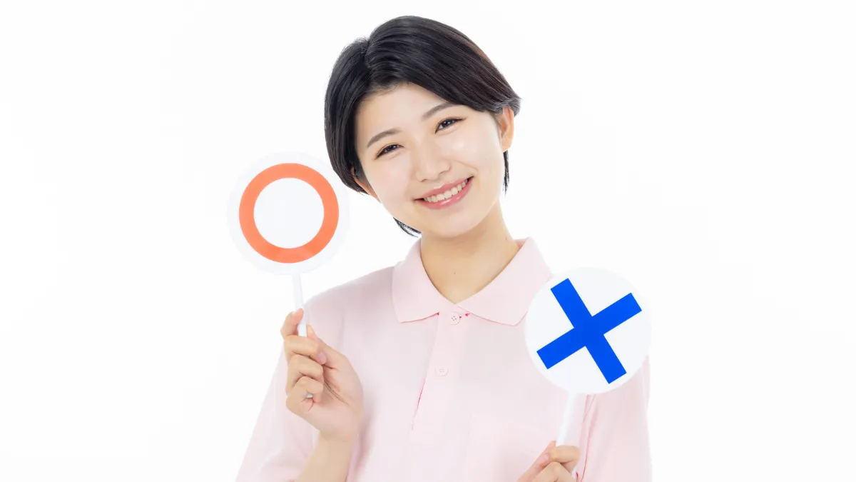 マルとバツの札を持つ看護師