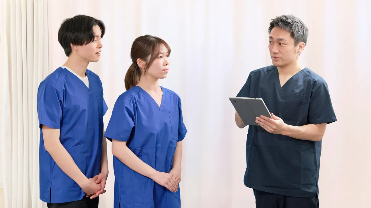 タブレットを見ながら後輩を指導する柔道整復師