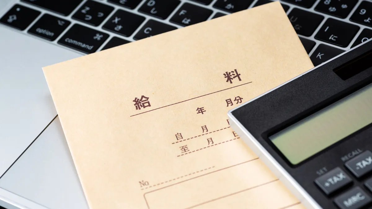 薬剤師の年収を確認するための給与袋とパソコンと電卓