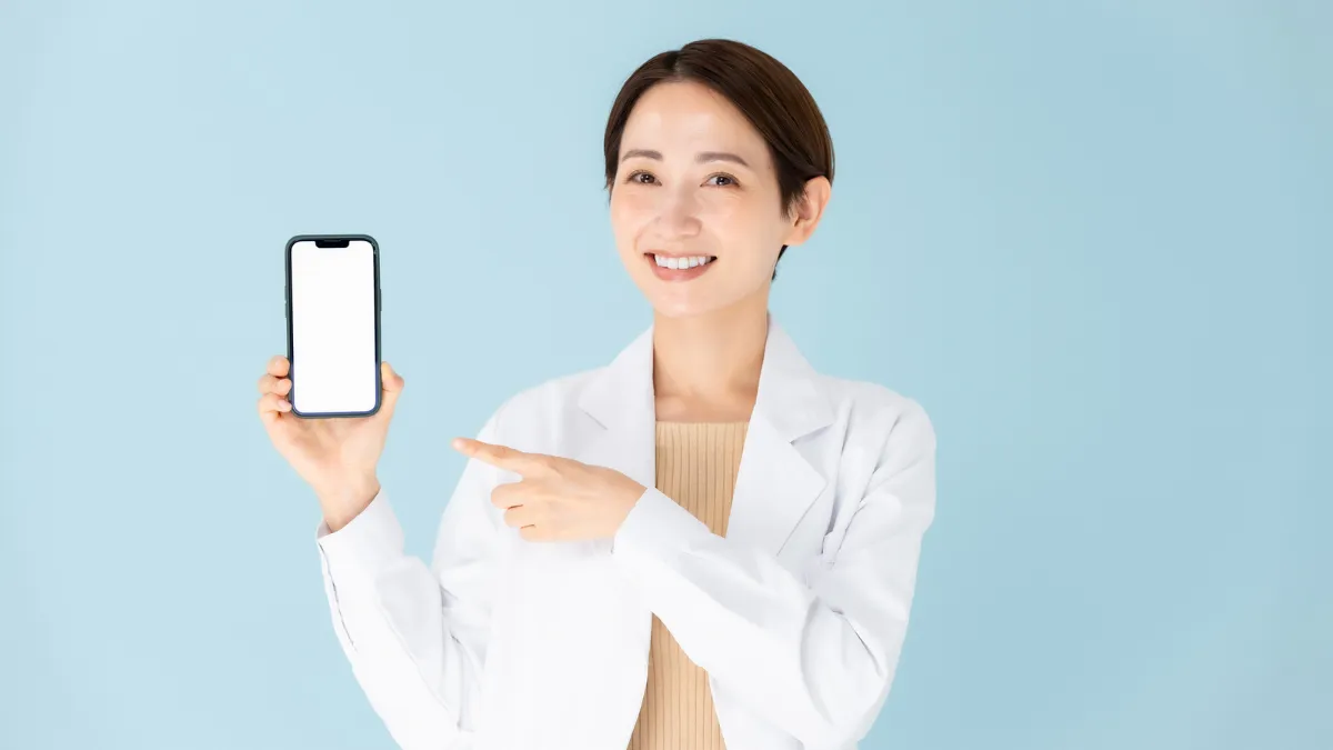 スマートフォンを指さして笑顔の薬剤師