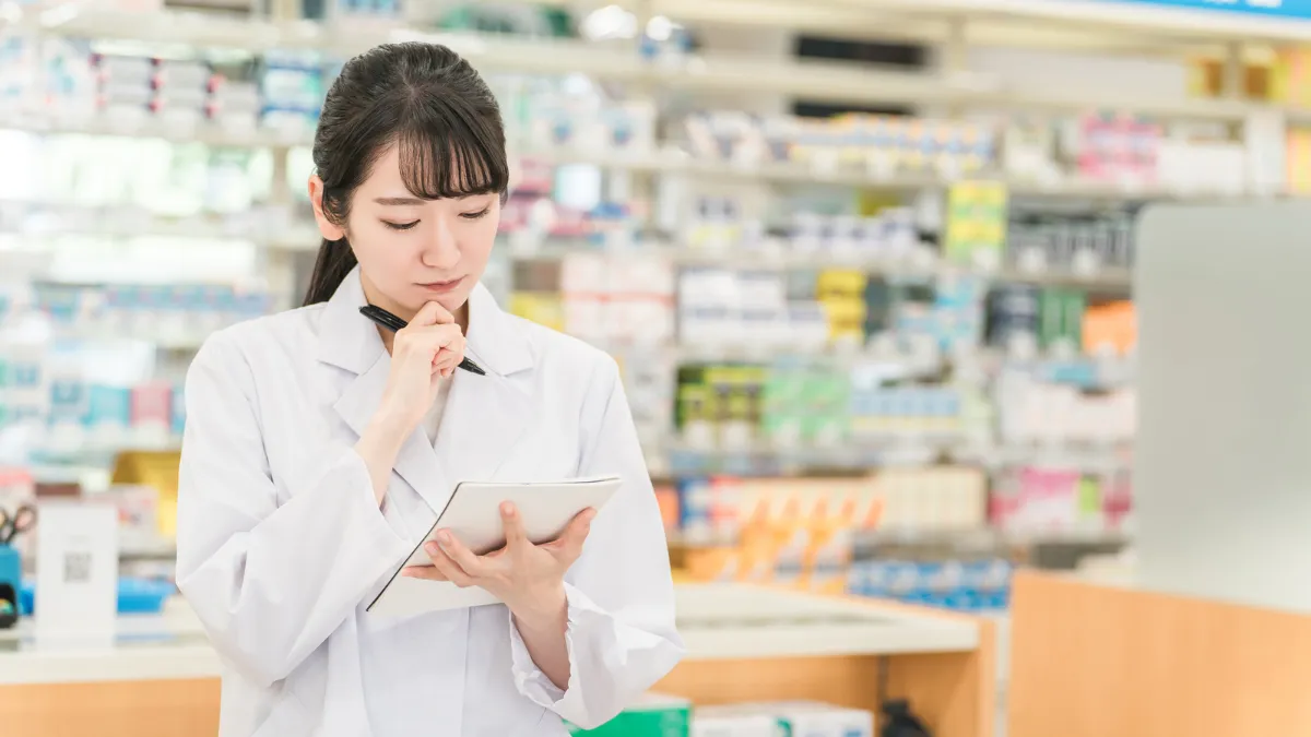 ノートを前に考え込む薬剤師の女性