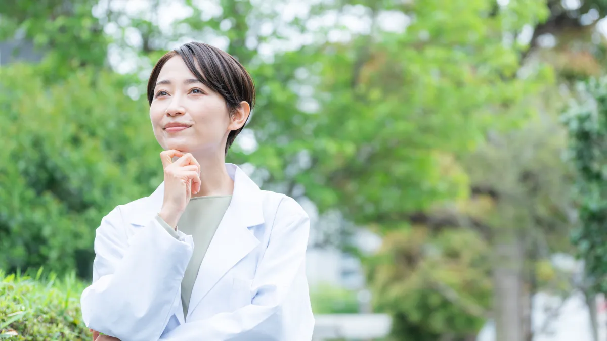 白衣を着て屋外で考える女性の医療職