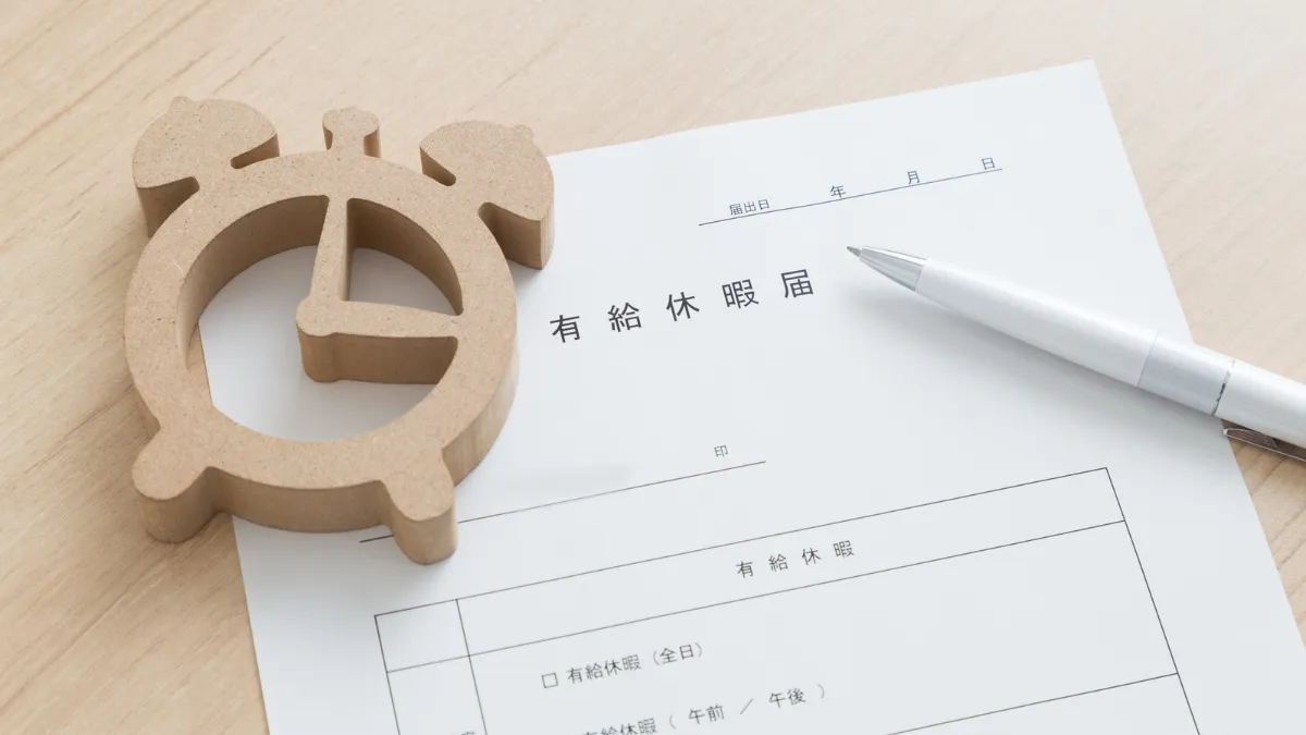 机の上に置かれた休暇届の用紙とペン
