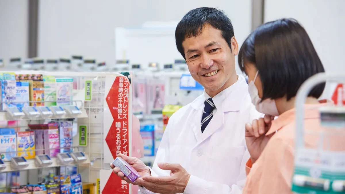 ドラッグストアで商品を説明する男性薬剤師