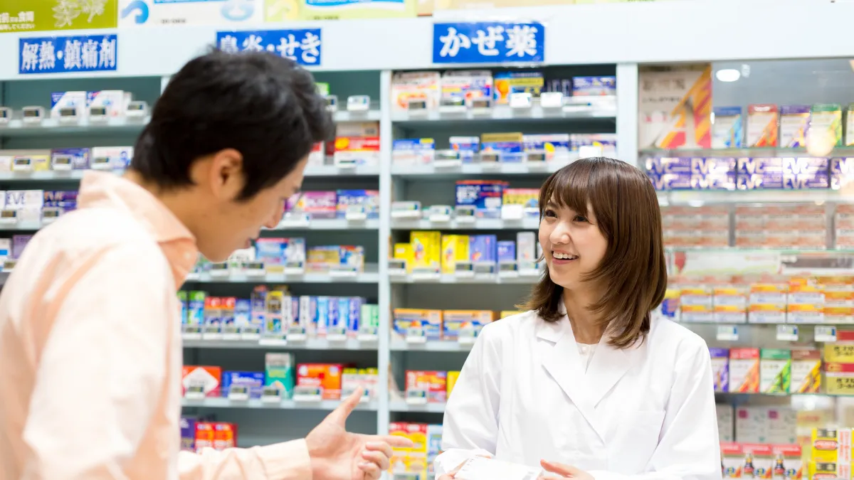 ドラッグストアで薬について説明する薬剤師