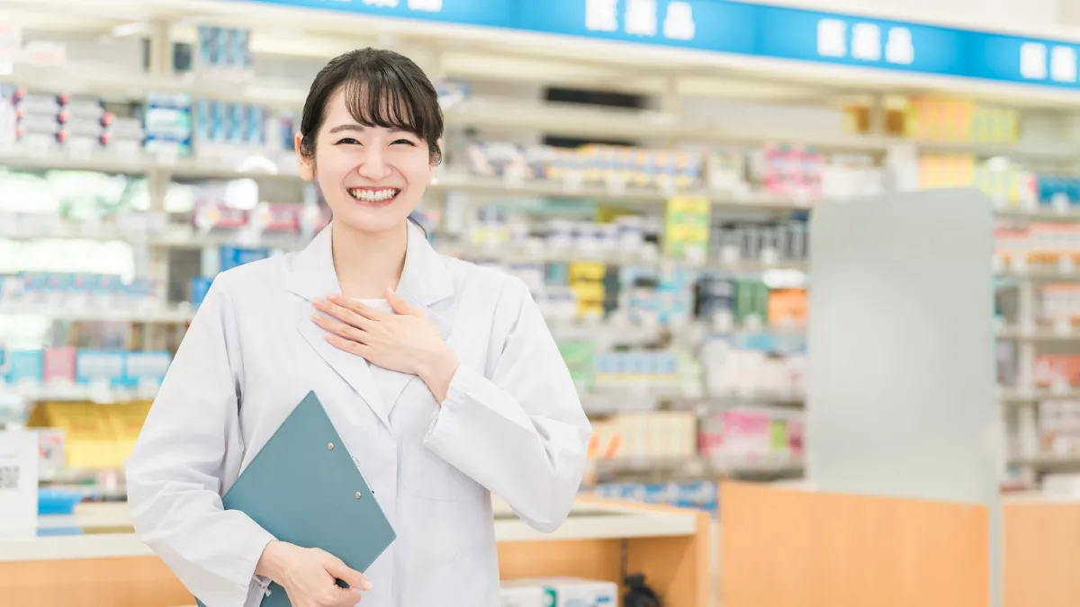 ドラッグストアで胸に手をあてて笑顔を見せる薬剤師