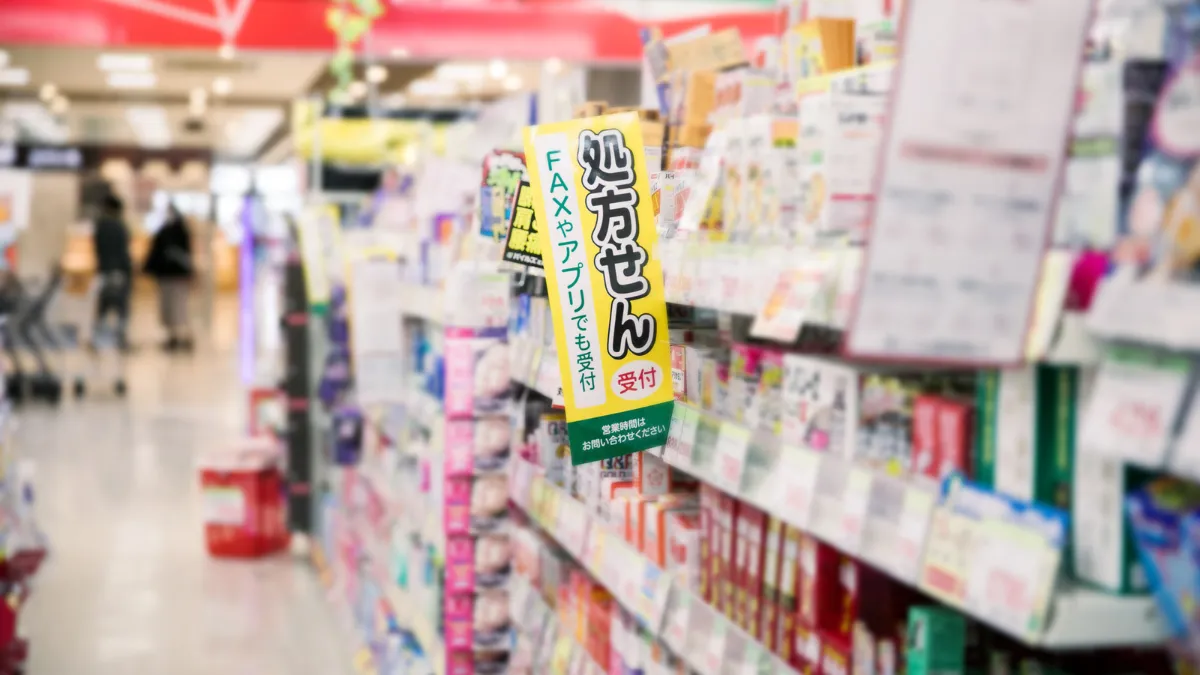 処方せん受付の案内が掲示されたドラッグストアの陳列棚