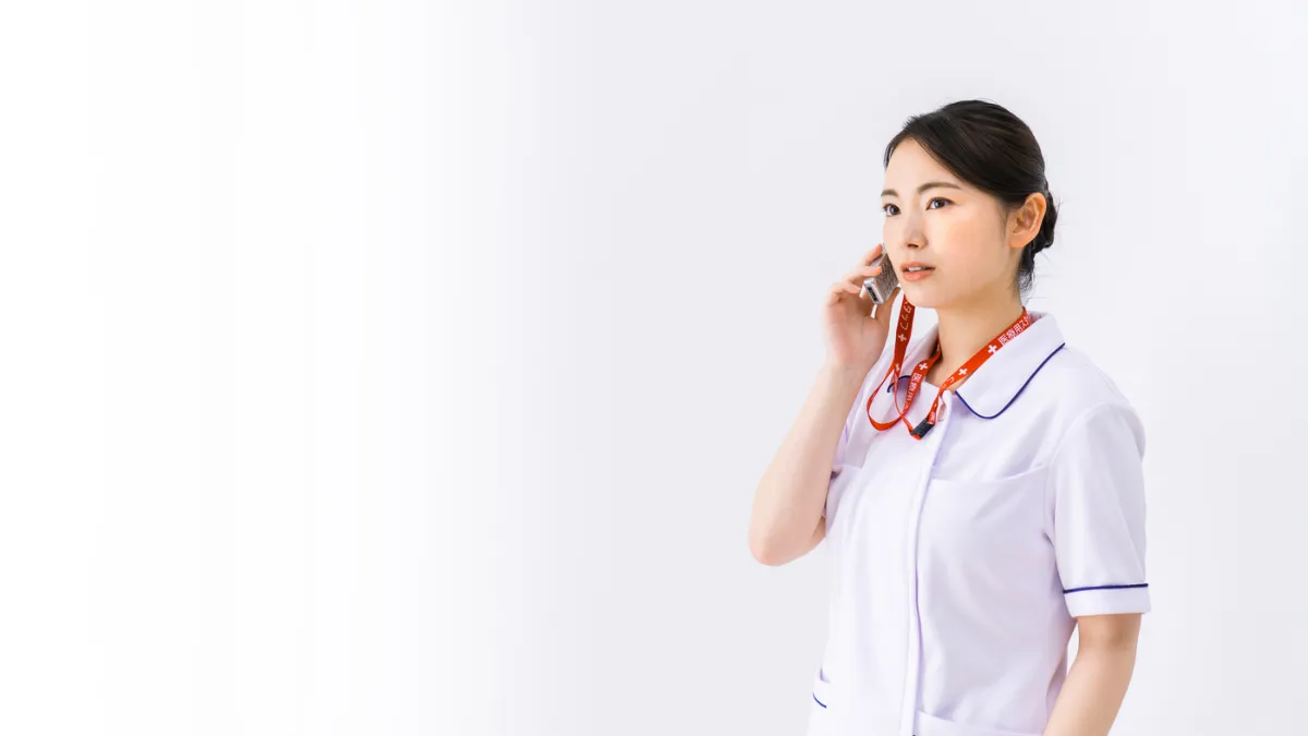 険しい表情で電話対応をする看護師