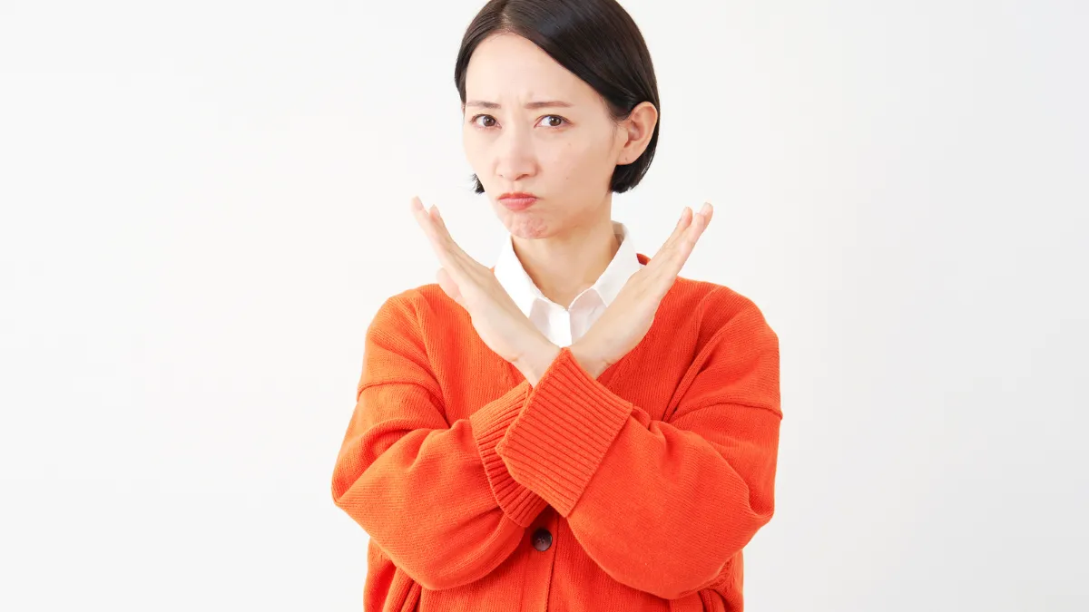 胸の前でバツマークを示す女性