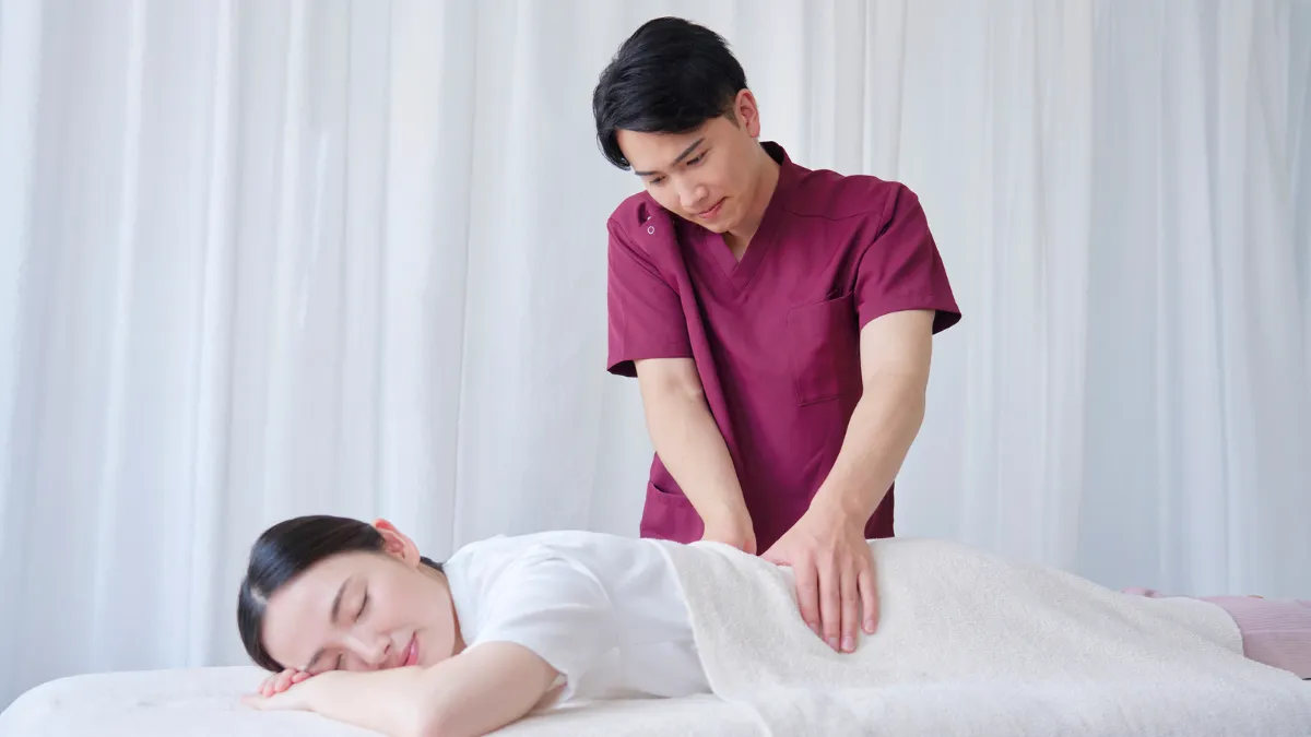 腰にマッサージのような手技を行う男性の柔道整復師