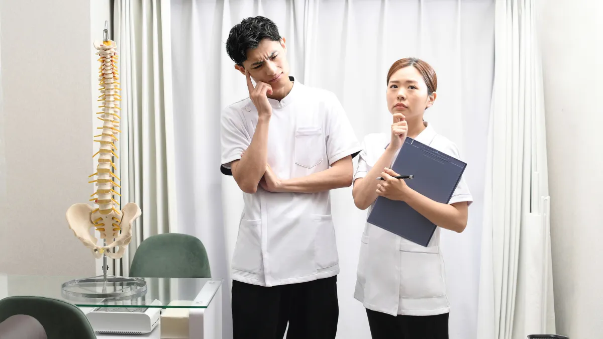 バインダーを前に頭を抱える柔道整復師の男女