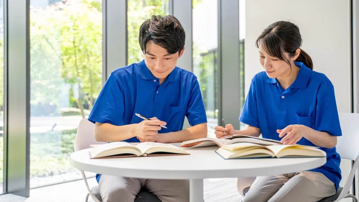 参考書を開いてメモを取りながら勉強する男女