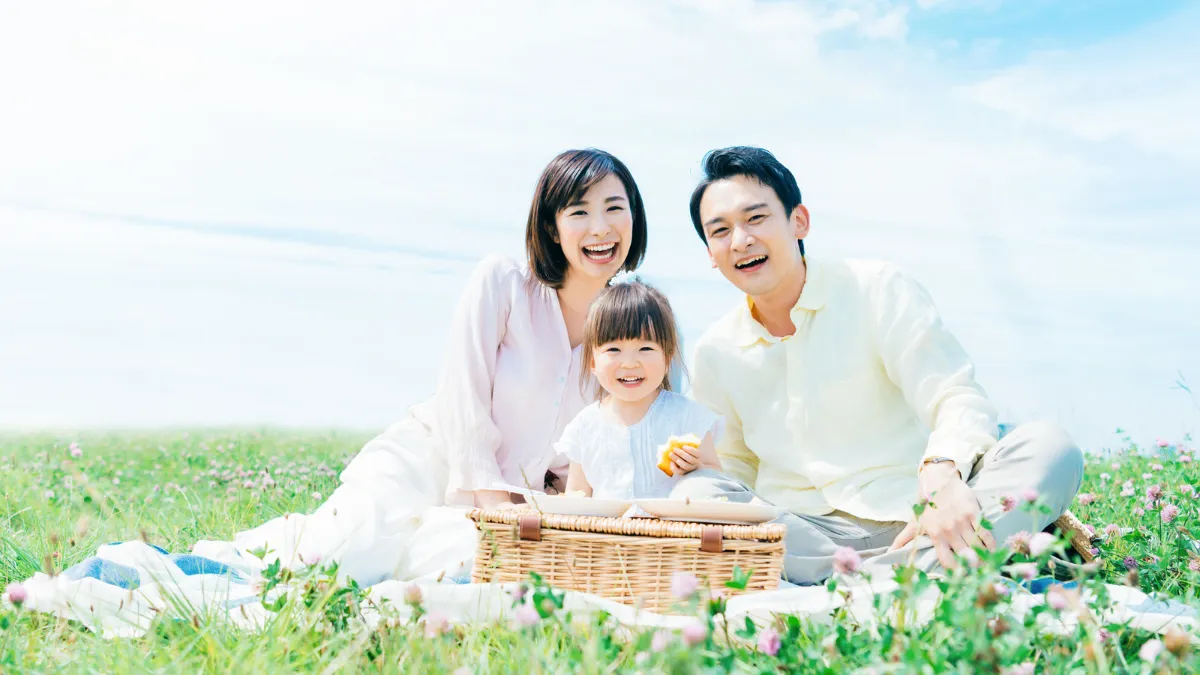 花畑の近くでピクニックを楽しむ夫婦と子ども