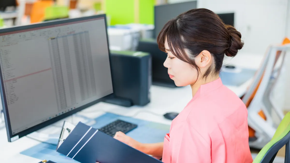 パソコンとバインダーで書類作業を進める看護師