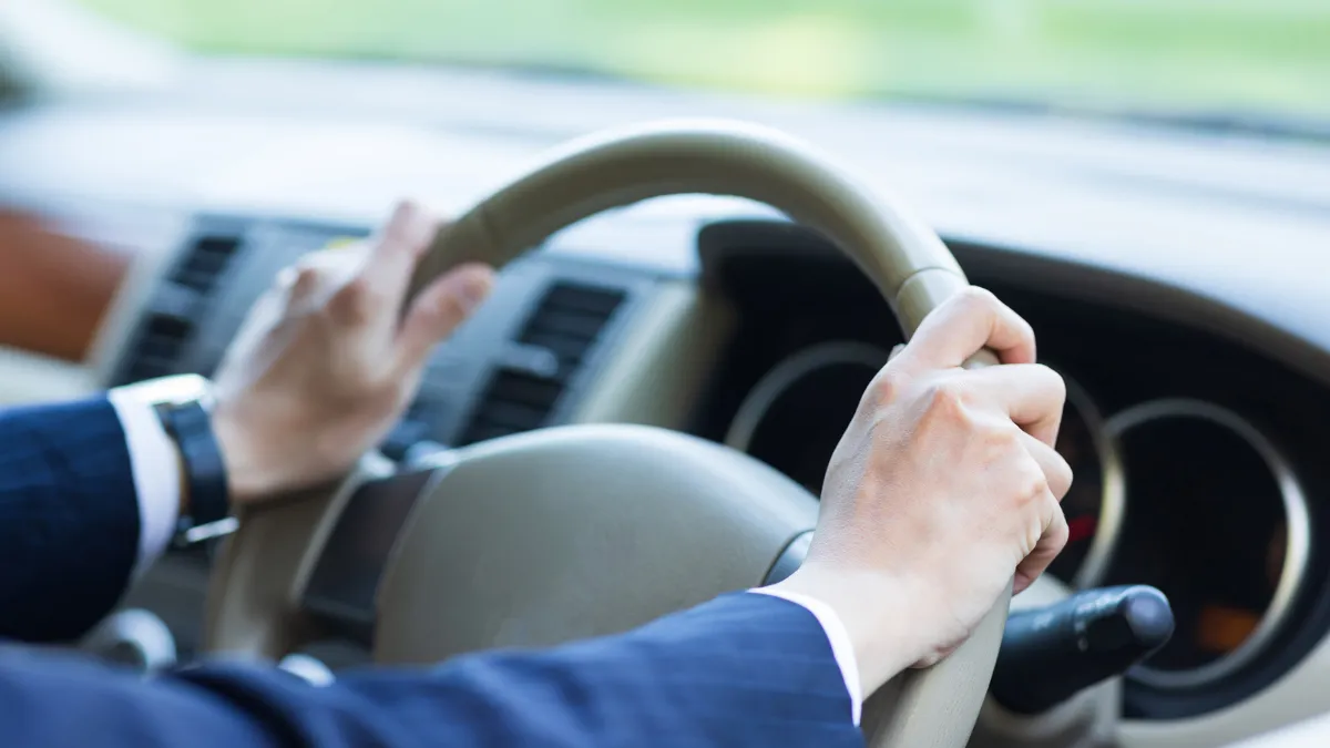 スーツを着て車を運転する人の手元