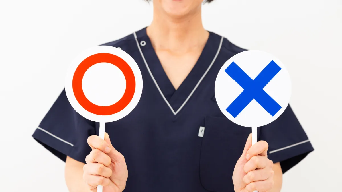 〇と×の札を挙げて業務範囲の可否を示す医療職の女性