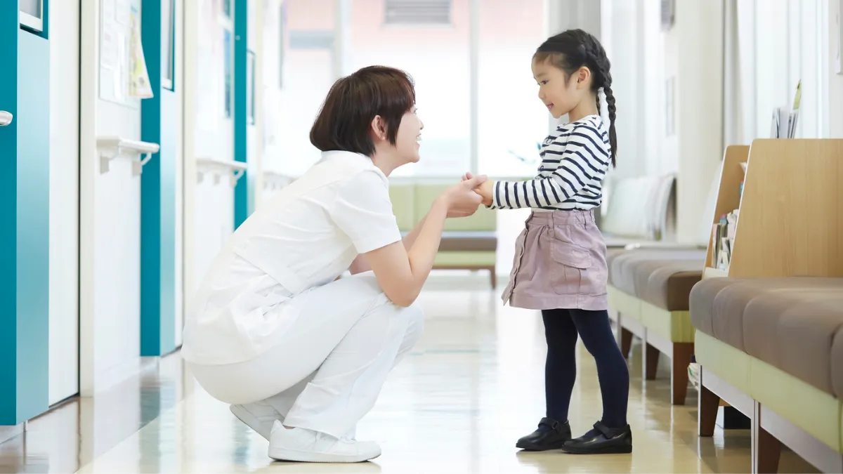 子どもと手をつないで笑顔を見せる看護師