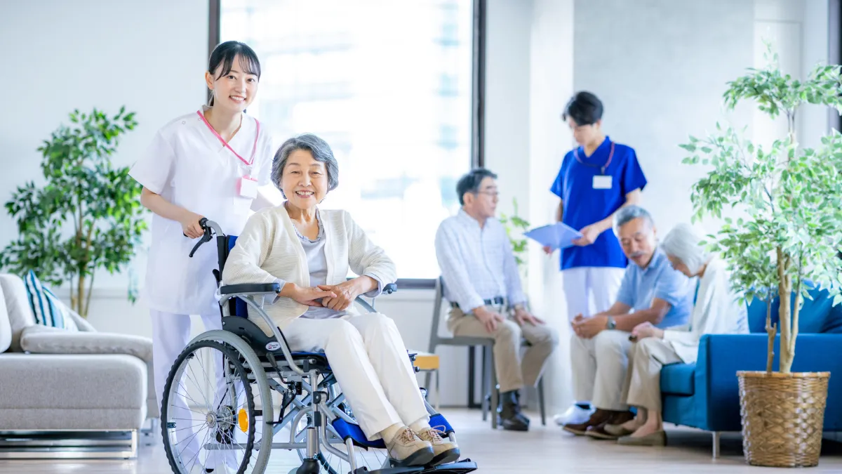 車いすの高齢の患者さんに笑顔で寄り添う看護師